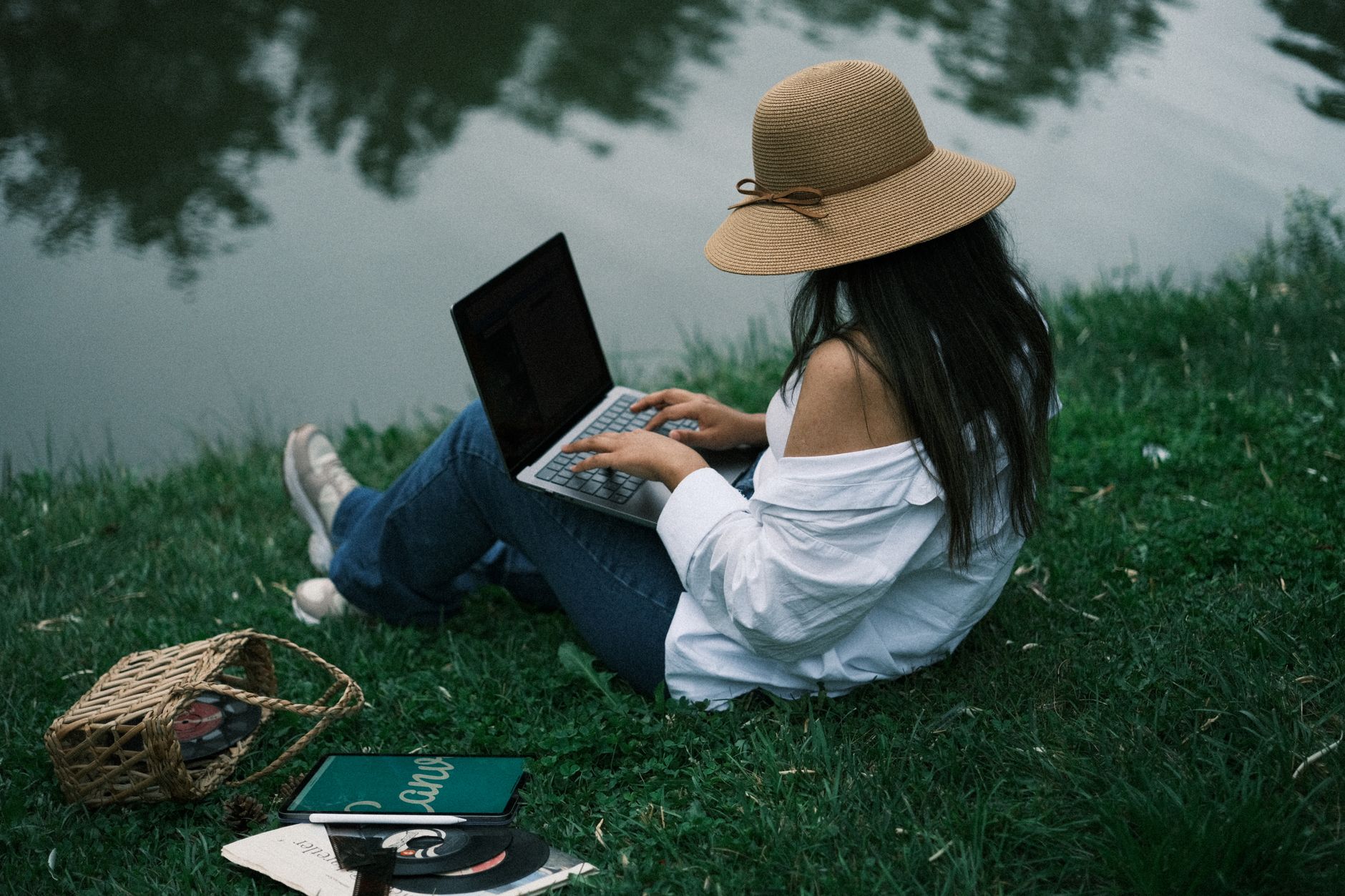 Une personne travaille sur son ordinateur portable au bord d'un lac calme, illustrant un travail flexible depuis chez soi.